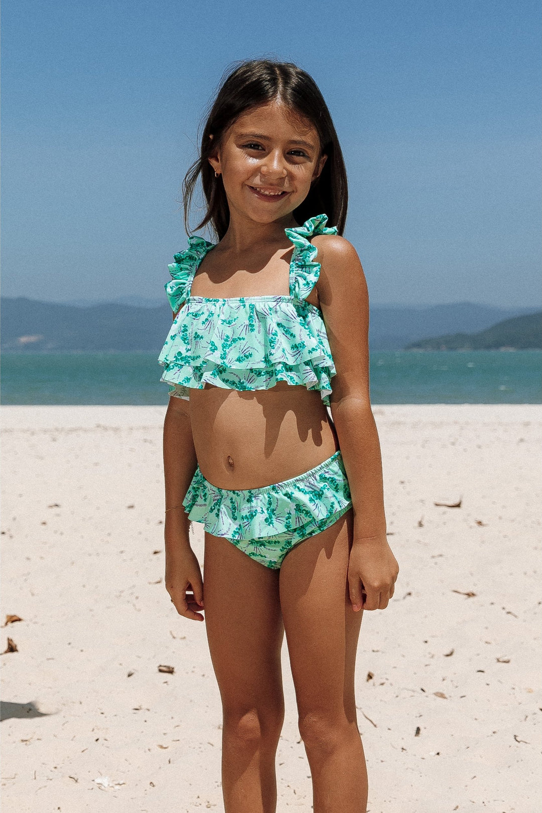 Encante com Moda Praia Infantil, com nosso Biquíni Infantil! Top e Calcinha Adornados com Babadinhos e Detalhes Dourados para um Visual Encantador. Na Estampa Lavanda, da Lili Sampedro.