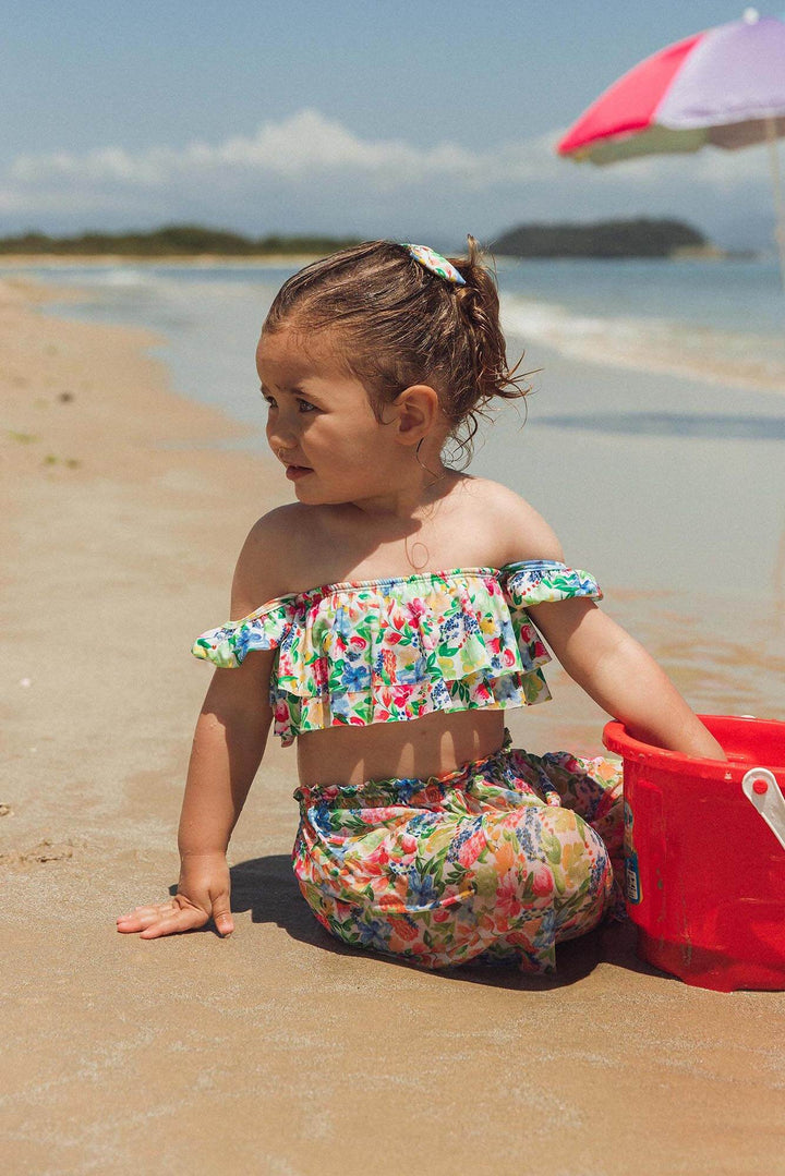 Modelo bebê usando biquininho Vicky e Calça Maya combinando com lacinho de cabelo na estampa primavera