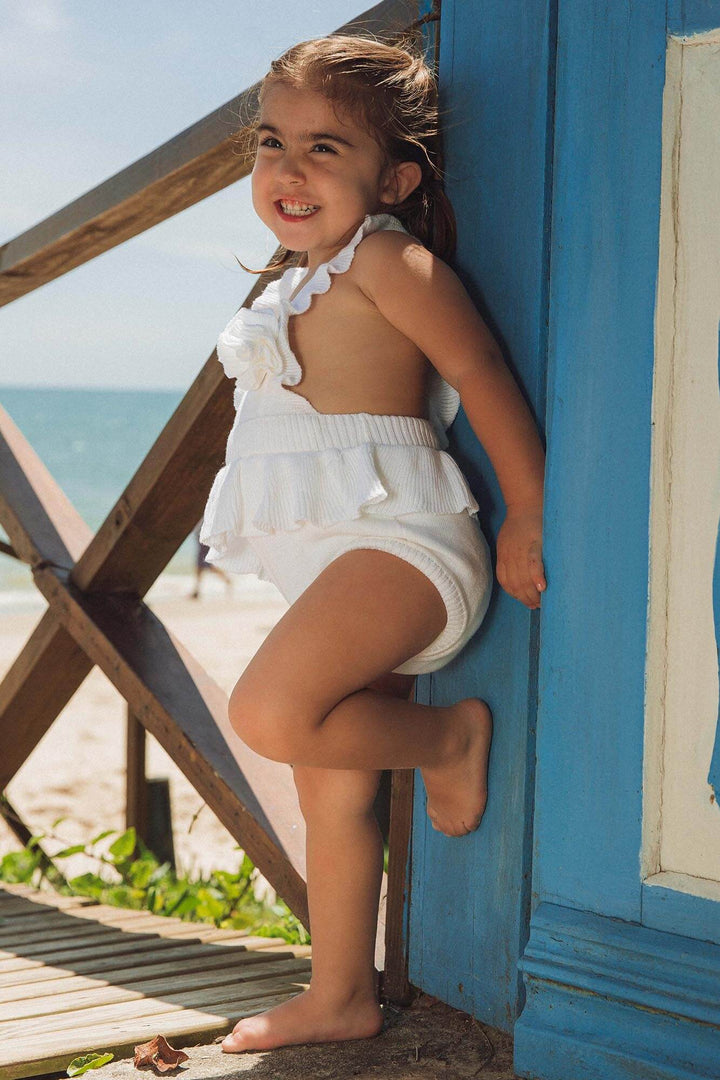 Modelo bebê vestindo body de tricot com babado e flor da Lili Sampedro na cor Branca