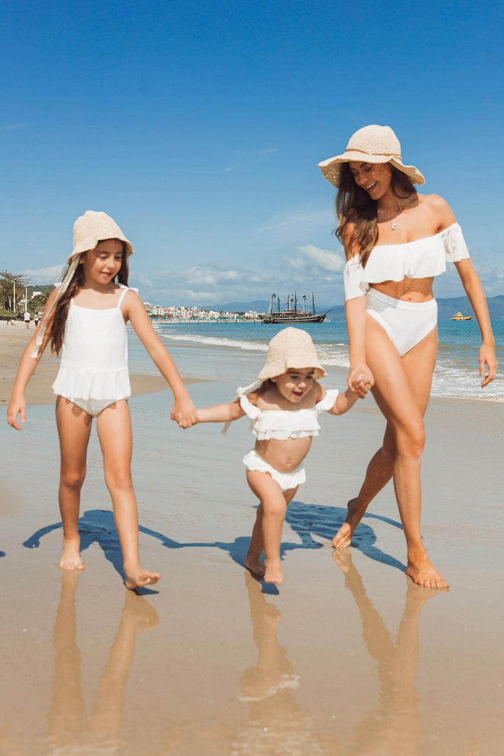 Mãe e filhas usando modelo de chapéu de praia combinando, da Lili Sampedro