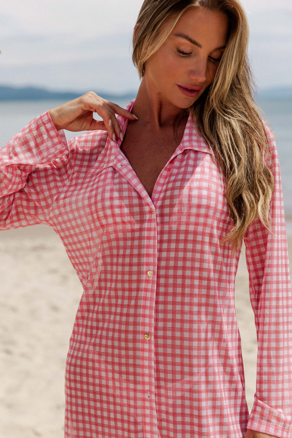 Conheça nossa Chemise saída de Praia, com mangas compridas e comprimento médio, uma opção elegante e moderna para os dias de Sol na praia, com detalhes em dourados,  feita de tule, proporcionando um visual encantador e confortável. Na estampa Vichy Rosa, da Lili Sampedro.