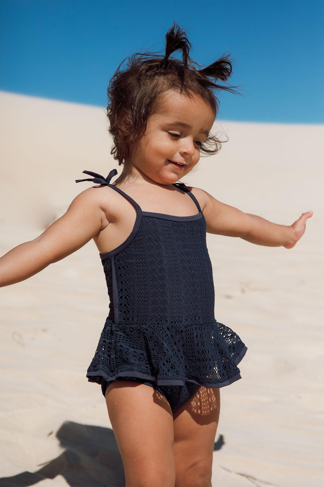 Bebe vestindo maio infantil de praia de renda com babadinhos azul marinho da Lili Sampedro