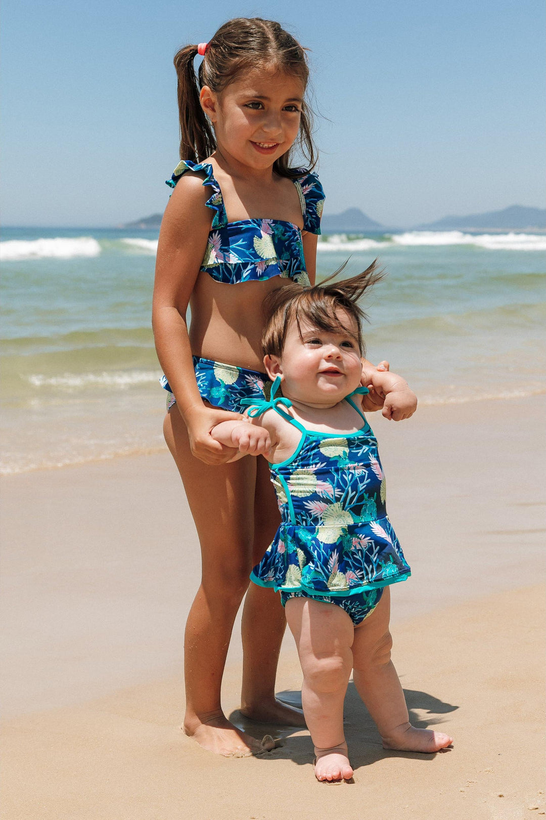 Criancas vestindo biquíni infantil e maio infantil de praia na estampa tartaruga azul