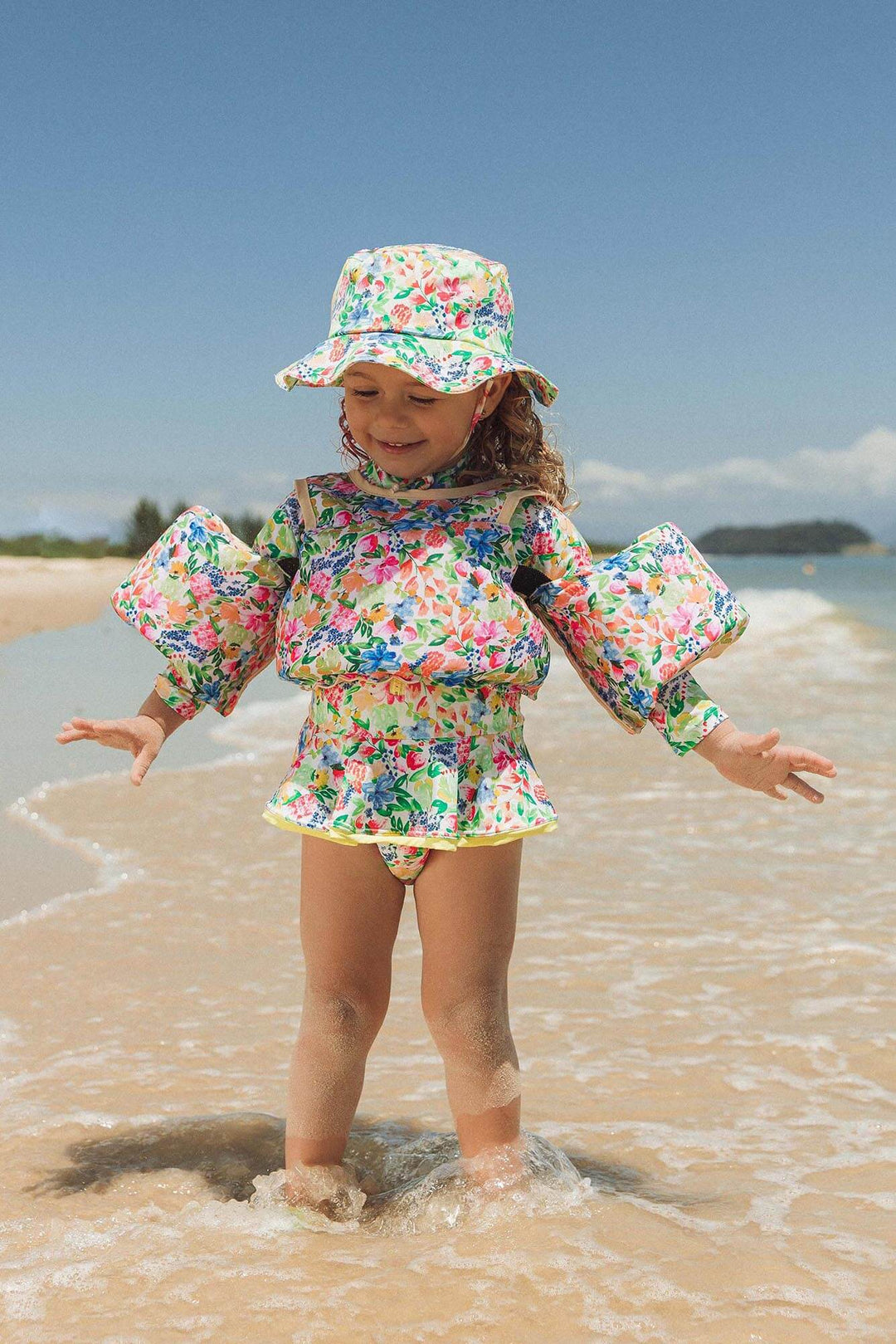 menina usando roupa de praia toda combinando com proteção UV e boia na estampa primavera