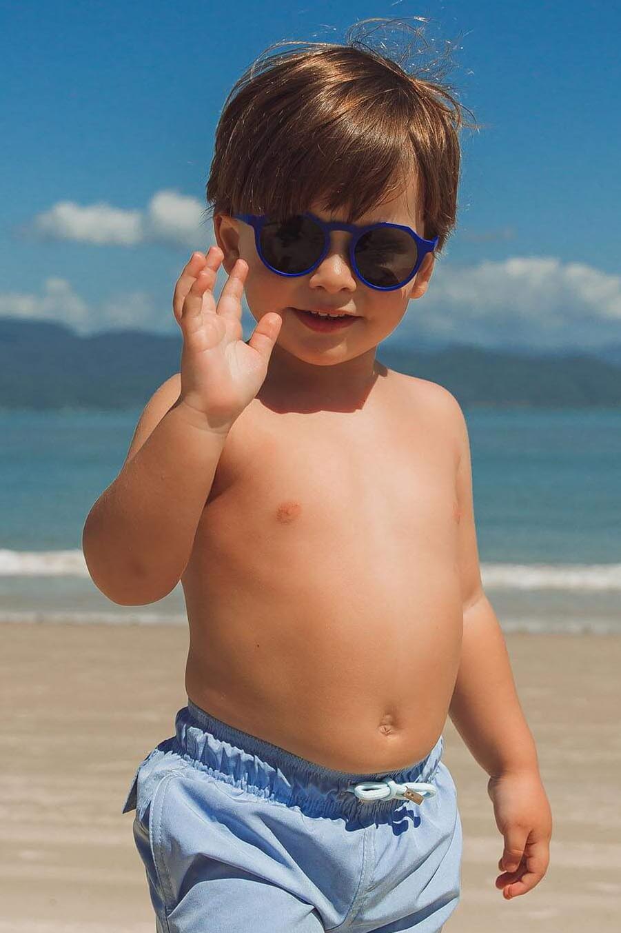 Modelo usando óculos de sol azul combinando com short de banho da Lili Sampedro