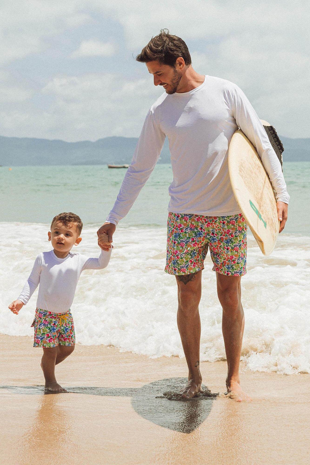 Pai e filho usando look de praia combinando com short de banho e camiseta UV 