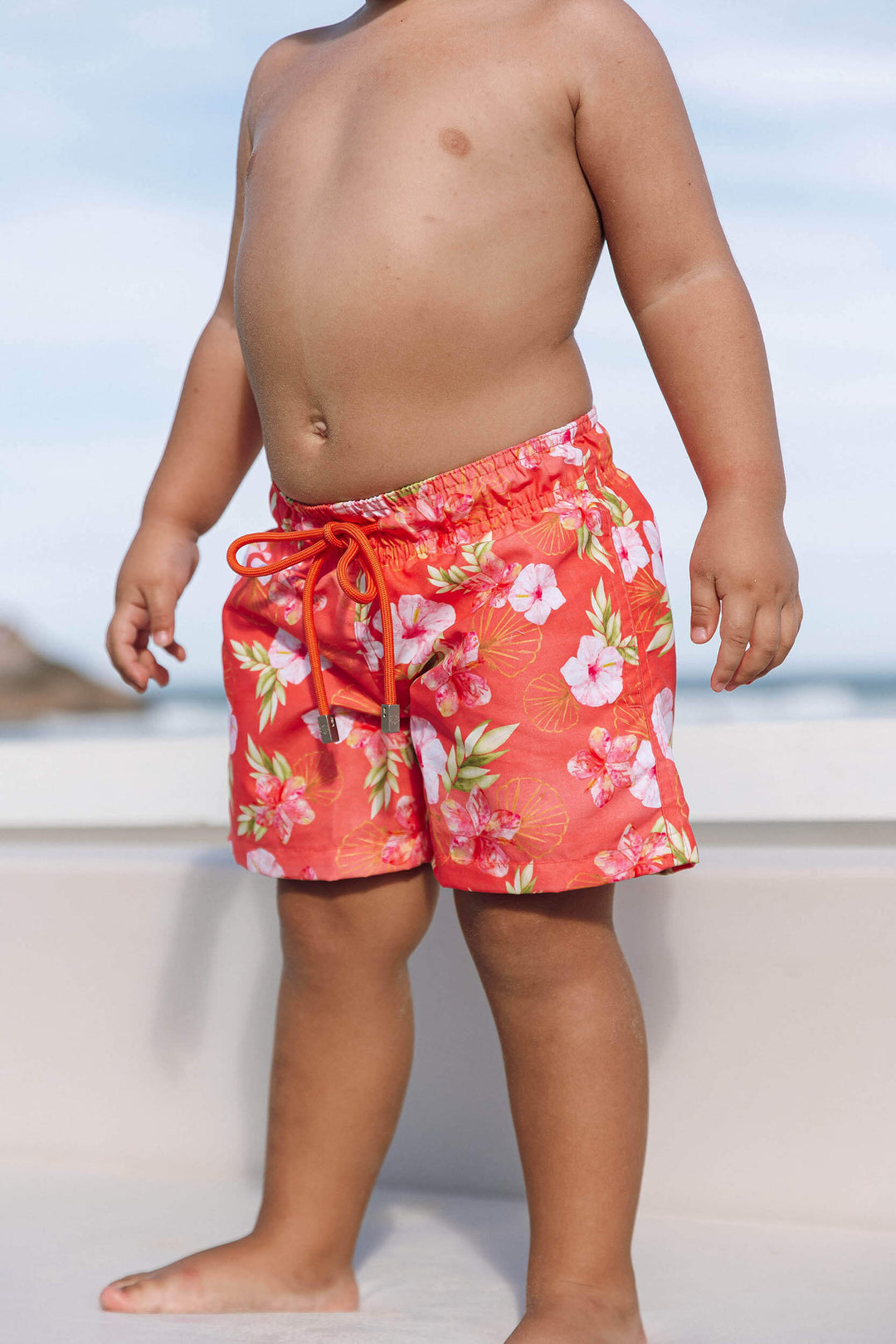 Bermuda de Praia para Meninos, para idades de 6 meses a 14 anos. Com Bolsos Frontais, este short proporciona conforto e praticidade, para curtirem momentos de diversão, na praia. Na estampa exclusiva, Hibiscos Versão Coral, da Lili Sampedro.