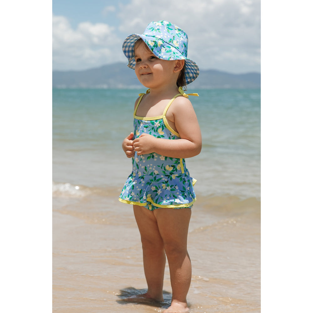 Maio Infantil de Praia Feminino com Babadinhos na Estampa Limões Com Look para a Família Toda Combinando da Lili Sampedro Moda Praia Infantil. Na foto bebê vestindo chapéuzinho vendido separadamente.